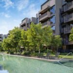 Beautiful resort-style lap pool surrounded by landscaped gardens and modern condo blocks, offering tranquil outdoor living.
